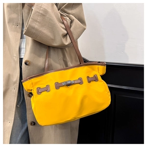 Details einer großen gelben Nylontasche mit Lederriemen und Metallverschluss am Modell