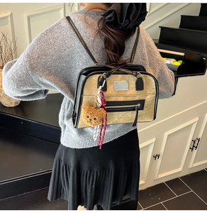 Détail d'un sac à dos vintage bicolore avec pendentif ours et plaque métallique chic
