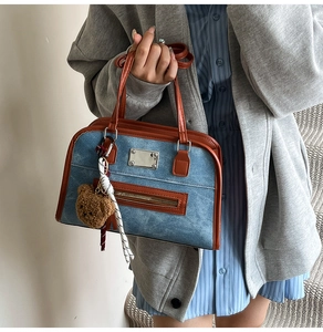 Detail of denim shoulder bag with brown leather trim and cute plush bear keychain charm