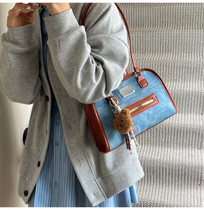 Detail of vintage denim tote bag with brown leather trim and cute plush bear charm