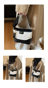 Detail of quilted two-tone shoulder bag with wide strap and gold fashion plaque