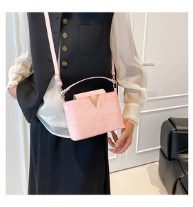 Detail of pink faux crocodile leather handbag with golden V buckle and shoulder strap