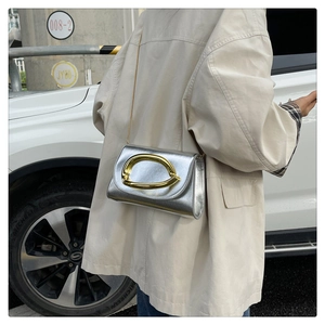Style urbain pour ce sac argenté métallisé à chaîne avec sa grande boucle dorée