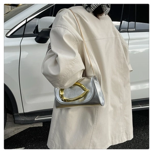 Détail du sac de soirée en cuir argenté avec poignée ovale dorée et bandoulière chaîne