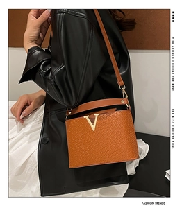 Detail of woven texture shoulder bag with gold V-clasp and adjustable leather strap
