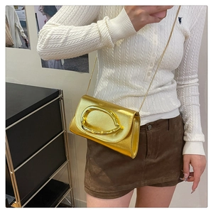 Détail d'un sac à main doré métallisé avec boucle ovale et fine bandoulière chaîne