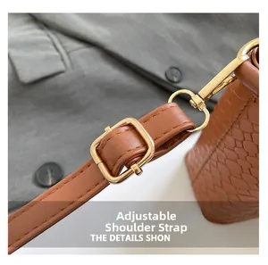 Detail of brown woven texture bag featuring an adjustable strap and gold metal hardware