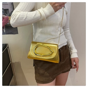 Détail d'un sac bandoulière doré métallisé avec grande boucle ovale et bandoulière chaîne