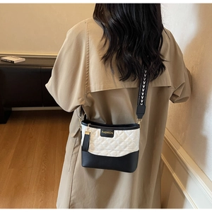 Detail of quilted two-tone crossbody bag with gold FASHION lettering and tassel detail