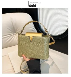 Detail of gold woven texture on luxury square handbag with metallic V logo
