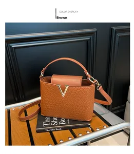 Detailed view of woven texture and gold V-logo on a structured brown leather tote bag