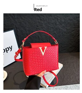 Detail showing red textured handbag with gold V-logo and elegant top handle strap