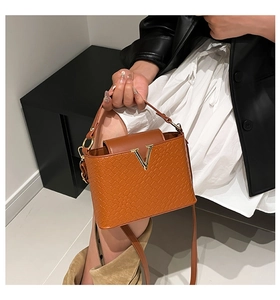 Detail of retro brown tote bag with woven texture, gold V-logo and sturdy handle
