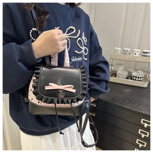 Dettaglio mini zaino con bordo in pizzo nero, fiocco rosa e ciondolo a cuore in metallo