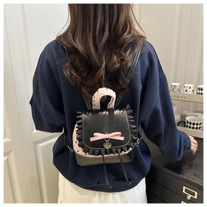 Detail of pink bow and lace trim on a sweet style mini backpack with heart pendant