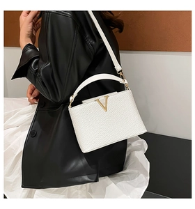 Chic white crocodile embossed bag with gold V hardware styled on a black leather jacket