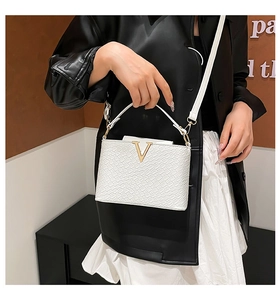 Detail of white embossed leather handbag with gold V metal hardware and crossbody strap
