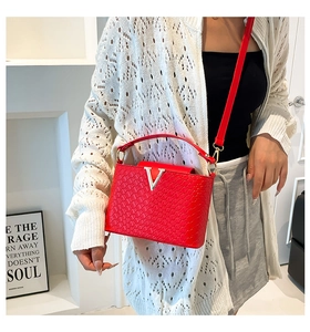 Close-up of red woven leather texture and elegant gold V-shaped metal buckle on the bag