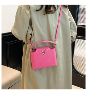 Detail van fuchsia roze crossbodytas van reliëfleder met zilveren V-vormige metalen gesp