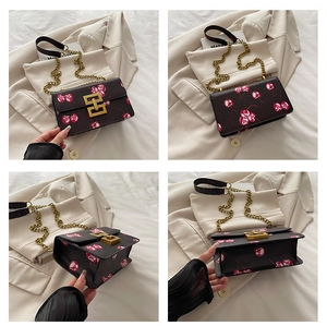 Close-up of cherry print crossbody bag with metal chain strap and flap closure details