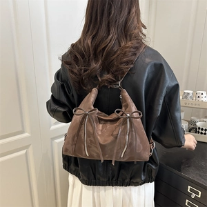 Sac cabas marron en cuir mat avec décoration de nœud porté par un mannequin