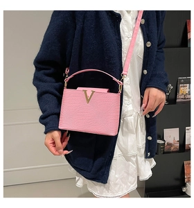 Model met een roze geweven leren handtas met gouden V-gesp en een verstelbare schouderriem
