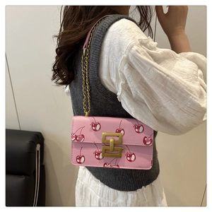 Pink crossbody bag with cherry prints and vintage gold chain strap shown on model