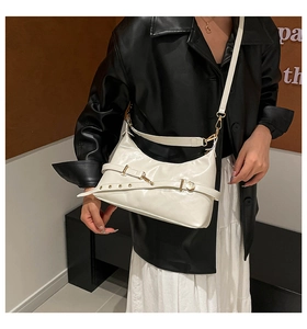 Detail of cream white crescent underarm bag with adjustable strap on a leather jacket