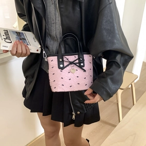 Pink crossbody bag with black bow patterns and heart pendant in a stylish outfit look