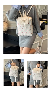 Detail of cream backpack with red bow print, 3D bow decoration and pearl pendant charm