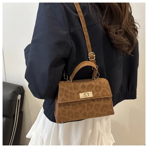Detail of leopard print crossbody bag featuring a golden twist lock and suede texture