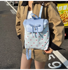 Detail of light blue bow backpack featuring pearl pendant and red ribbon patterns