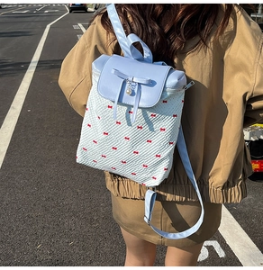 Detailed outdoor shot of a light blue bow and pearl charm on a white quilted backpack