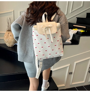 Detail of Korean style backpack featuring red bow prints and a pearl pendant charm
