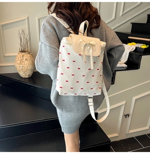 Rear view of a cream mini backpack with red bow embroidery and a pearl pendant detail