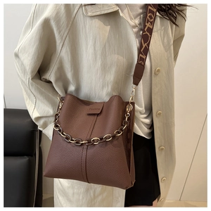 Detail of brown litchi pattern bucket bag with retro chain and geometric strap