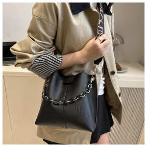Detail of black lychee grain leather bucket bag with chain and printed strap