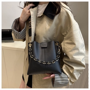 Close-up of black lychee grain leather bucket bag with decorative gold chain and strap