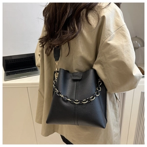 Detail of black lychee grain leather bucket bag featuring gold chain and logo flip cover