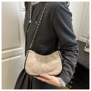 Detail of beige suede crossbody bag with quilted diamond pattern and gold chain strap