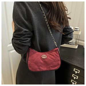 Detail of burgundy quilted suede shoulder bag with gold chain strap on a model