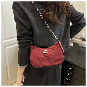 Detail view of burgundy quilted crossbody bag with gold hardware worn by model