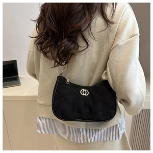Detail of black quilted suede shoulder bag with gold hardware and circular buckle