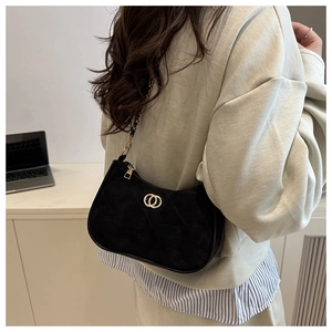 Detail of black suede underarm bag with gold chain strap and quilted diamond stitching