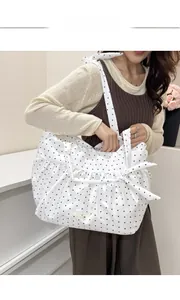 Detailed view of the knotted shoulder strap and ruffles on the polka dot tote bag