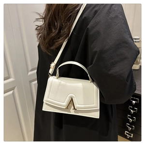 Détail du sac à bandoulière blanc en cuir avec boucle métallique dorée en forme de V