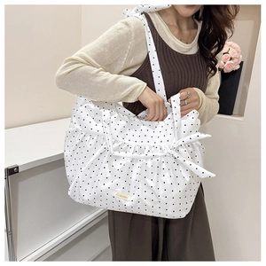 Polka dot tote bag with bow detail and matching shoulder strap on a female model