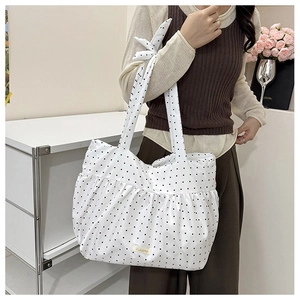 Detailed view of white polka dot canvas tote with ruffled edges and bow strap