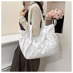 Close-up of a white pleated tote bag with black polka dots and dual shoulder straps