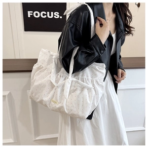 Close-up of white ruffled tote bag with pink polka dots and decorative bow handle